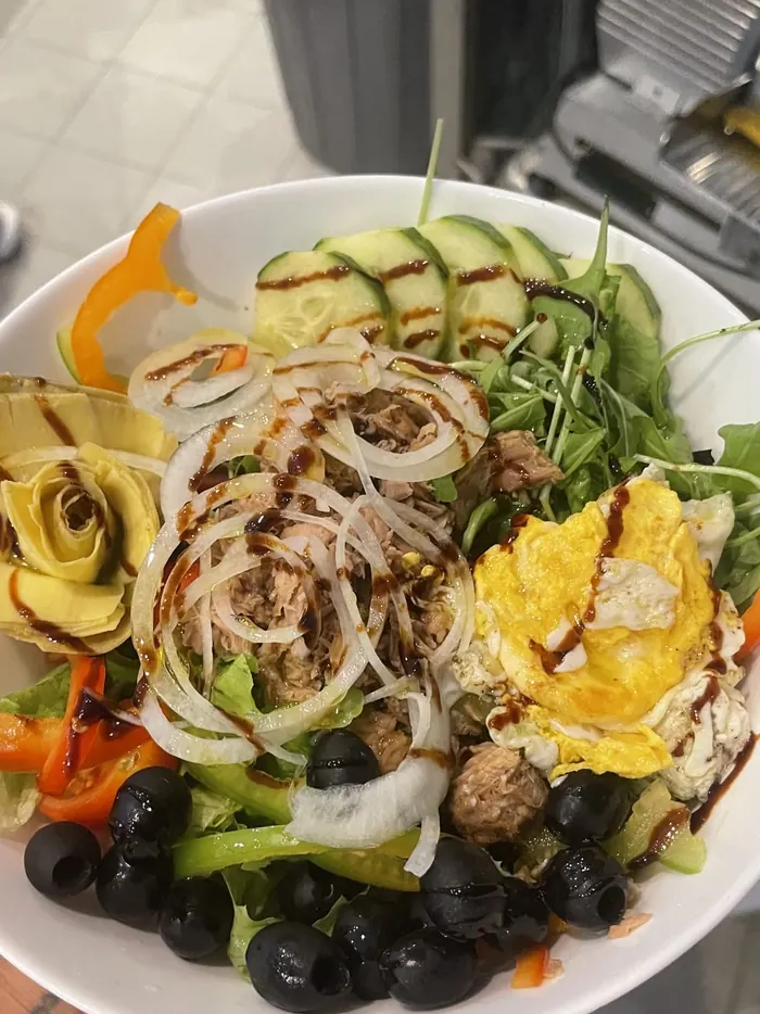 Großer Salat mit Thunfisch, Zwiebelringen, schwarzen Oliven, Artischocken und Spiegelei