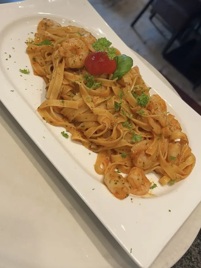 Tagliatelle mit Gamberetti in Tomatensauce, mit Petersilie und Basilikum